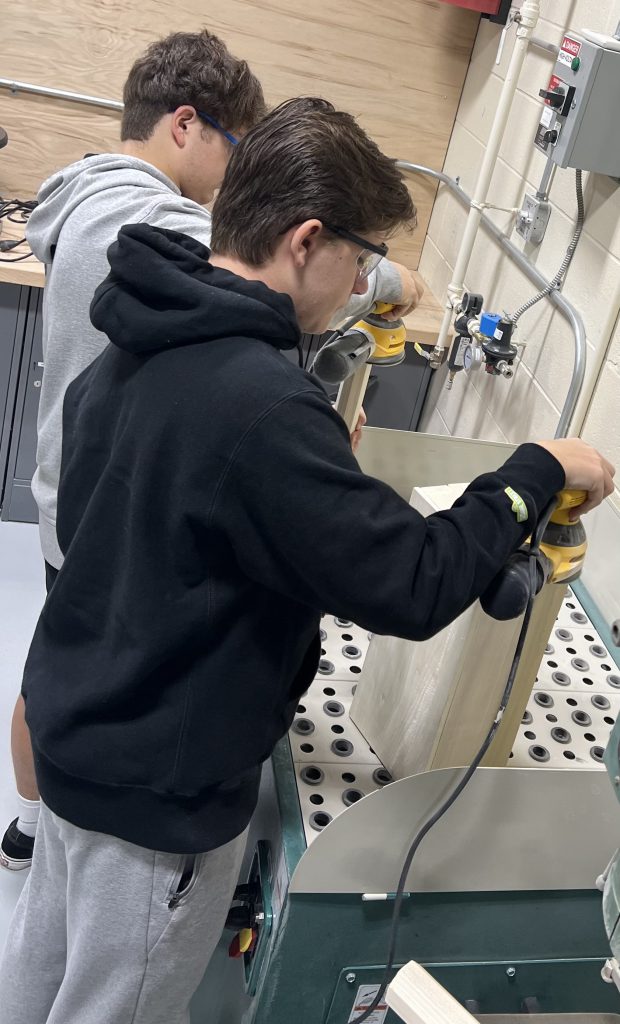 HS students in Manufacturing Systems work on their custom tool boxes using wood shop equipment and the laser engraver.