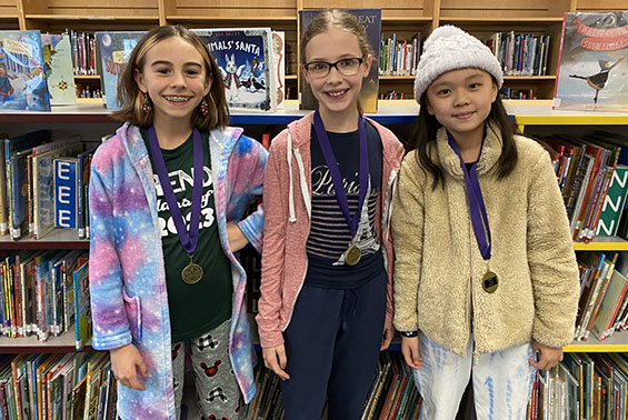 A photo of three girls in the library