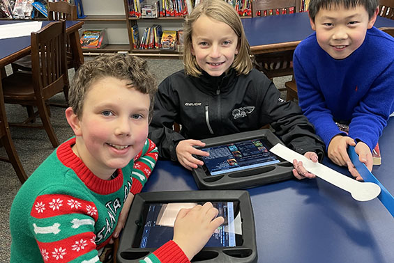 Skano students pop into the library and use iPads to search the catalog to find books. 