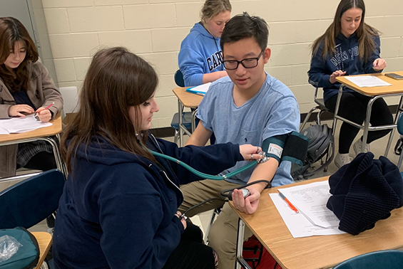 High school students in the Health Sciences for Medical Careers course practice career skills with oximeters,  sphygmomanometers, and stethoscopes.