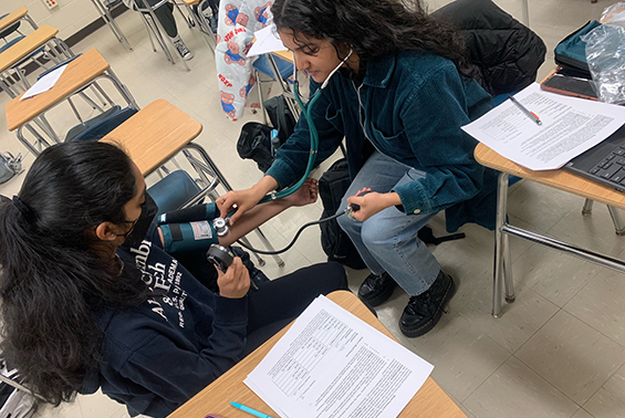 High school students in the Health Sciences for Medical Careers course practice career skills with oximeters,  sphygmomanometers, and stethoscopes.