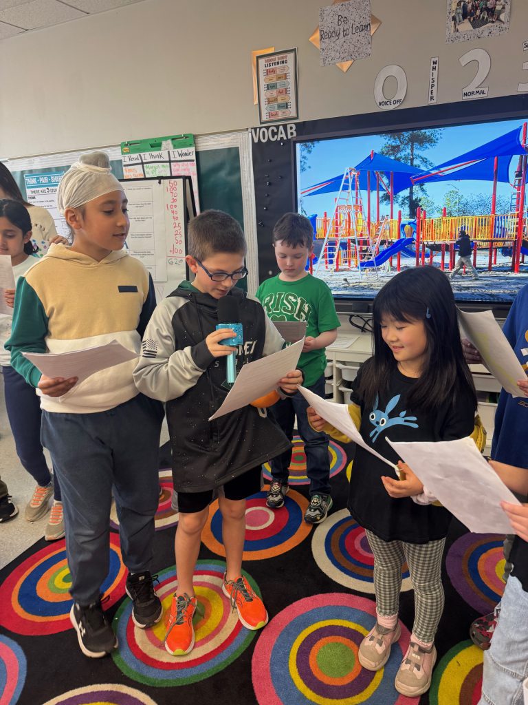 A group of students reading off paper.