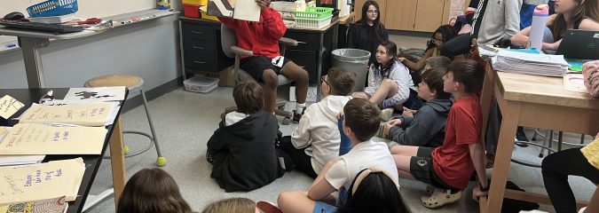 Sixth grade students in Mrs. Clermont’s Art class enjoy a story read by classmate Junior about 2 kids who are digging a hole trying to find something spectacular! The story is a precursor for a lesson on coloring gemstones.